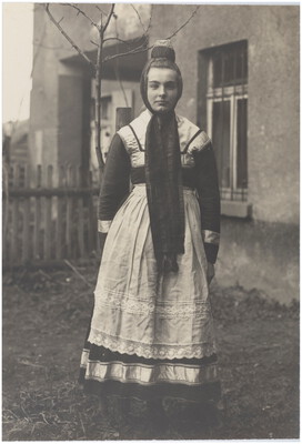 Junge Frau in Tracht vor einem Haus
